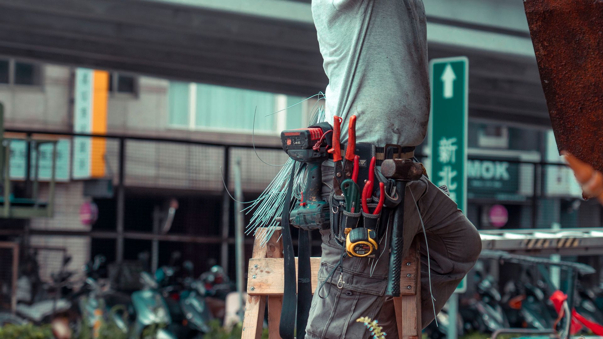 Handyman wearing a loaded tool belt with drill, pliers, and tape measure on a Sacramento job site